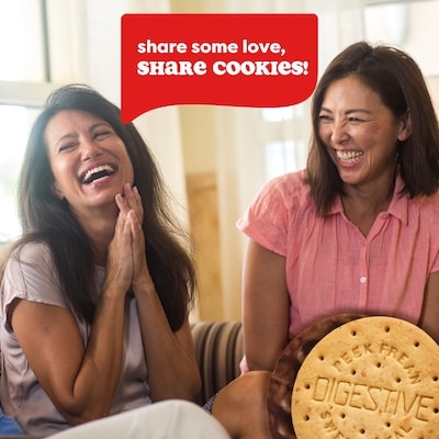 Two women laughing together with a speech bubble saying 'share some love, SHARE COOKIES!' and a Digestive cookie in the foreground.